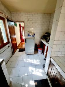 eine Küche mit weißem Fliesenboden und einem Kühlschrank in der Unterkunft Snow land cottage in Manali