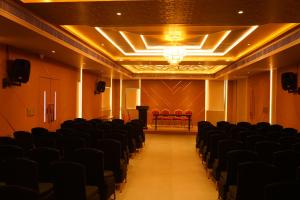 an empty room with black chairs and a stage at raj Regent kurichy in Putuppalli