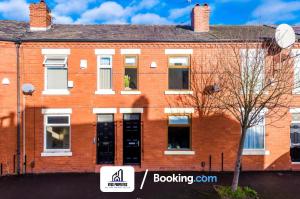 a red brick building with a clock on it at Weekly Stay By NYOS PROPERTIES Short Lets & Serviced Accommodation Manchester With Free parking in Manchester