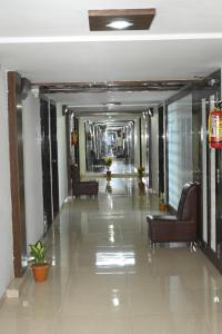 a hallway in a building with couches and chairs at Hotel Anand Inn in Vapi