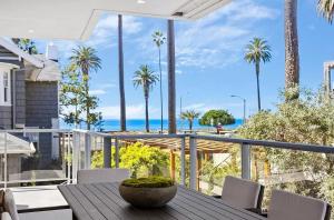uma mesa de jantar numa varanda com palmeiras e o oceano em Three Bedrooms and Four Bathrooms Superb Condo em Los Angeles