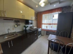 una cocina con armarios negros y una mesa y una cocina con fregadero en ЯРКАЯ ЗВЕЗДА НА КОСМОСЕ ! en Aktobé