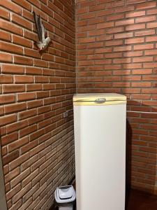 a white refrigerator in front of a brick wall at Pousada Nosso Bosque in Porto Belo