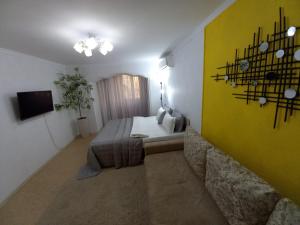 a bedroom with a bed and a yellow wall at ЯРКАЯ ЗВЕЗДА НА КОСМОСЕ ! in Aktobe