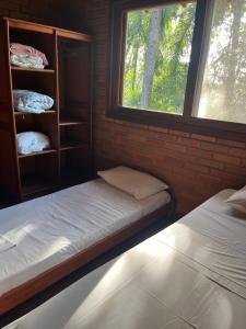 two beds in a room with a window at Pousada Nosso Bosque in Porto Belo