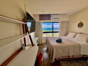 um quarto com uma cama e uma grande janela em Ondina Apart Hotel Residences em Salvador