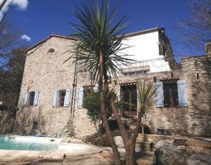 a large stone house with a palm tree in front of it at Les chambres d'hôtes du Moulin in Arles-sur-Tech