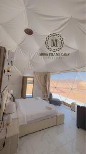 una camera con un letto in una tenda con un cartello di Moon Island Camp a Wadi Rum