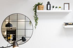 a mirror on a white wall next to a shelf at The Stanbury Residence by COQOON in Manchester