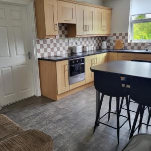 a kitchen with wooden cabinets and a table with chairs at Woodside guest house in Castlerock