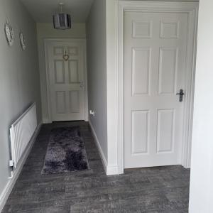 an empty hallway with a white door and a rug at Woodside guest house in Castlerock