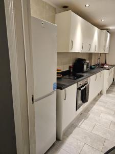 una cucina con armadietti bianchi e frigorifero di Hygis Great Home of Relaxations a Stoke on Trent