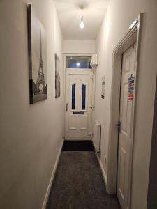 un corridoio con una porta bianca e immagini sul muro di Hygis Great Home of Relaxations a Stoke on Trent