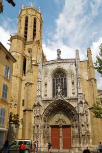 una gran iglesia con una torre y una puerta roja en Chambre d'hôtes en Provence, au pied du Luberon "Les Coquelicots" en La Tour-dʼAigues