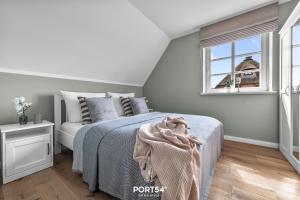 a white bedroom with a bed and a window at Reetdachkate Reethüüs Kappeln in Kappeln