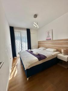 a bedroom with a large bed with a wooden headboard at Waves 605 River View in Sarajevo