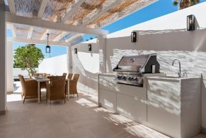 a kitchen with a grill and a table with chairs at 20600 - Luxurious Beachside Villa Near Marbella in Marbella