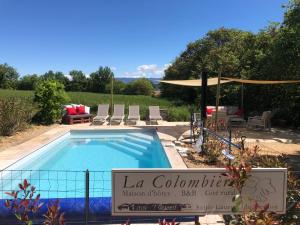 einen Pool in einem Garten mit Stühlen und einem Sonnenschirm in der Unterkunft La Colombiere du Château in Saint-Laurent-du-Verdon