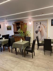 a restaurant with tables and a picture of a horse on the wall at Natura Panzió Szilvásvárad in Szilvásvárad