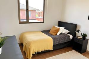 a bedroom with a bed with a yellow blanket and a mirror at Cómoda y acogedora casa en Buin in Buin