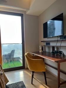 a room with a desk with a television and a chair at The Silver Clouds 17th Floor Studio Apartment in Ghaziabad