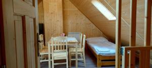 Cette chambre mansardée comprend une table et des chaises. dans l'établissement Apartmány u Bernardů, à Stožec