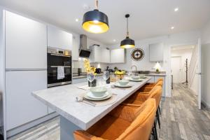 a kitchen with a large island in a kitchen with orange chairs at Spacious & Modern 4-Bedroom Townhouse in Manchester