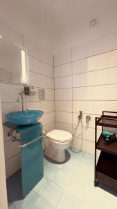 La salle de bains est pourvue d'un lavabo bleu et de toilettes. dans l'établissement Casa Prunilla, à Sarno