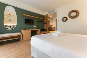 a bedroom with a large white bed and a mirror at Hotel Santanyi Port in Cala Figuera