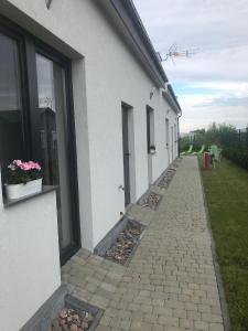 a walkway next to a building with a plane in the sky at Ferienwohnung in Paprotno mit Grill, Garten und gemeinsamem Pool in Gąski