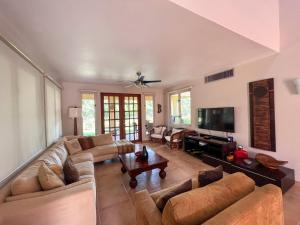 uma sala de estar com um sofá e uma televisão em Villa Iris 2 story ocean view villa w/ pool access em Vega Alta