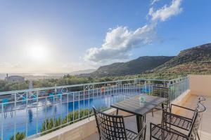 a balcony with a table and chairs and a swimming pool at Sundy Maria Apartments in Stoupa