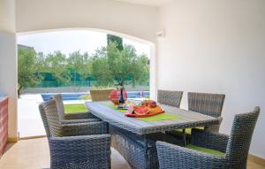 una mesa de comedor y sillas con un bol de fruta. en Villa Olivenbaum, en Kaštel Štafilić