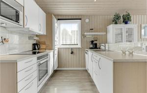 a white kitchen with white cabinets and a window at Holiday Home Sønderballevej Rødekro I in Diernæs +22 photos