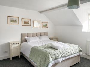 a white bedroom with a bed with a green blanket at Ashford Old Farm in Ilton