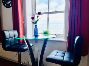 una mesa con un jarrón con flores en una ventana en Seafront & Dog Friendly Beautiful Ground Floor Flat, en Kent