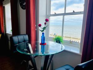 una mesa de cristal con un jarrón con una flor en una ventana en Seafront & Dog Friendly Beautiful Ground Floor Flat, en Kent