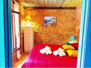 een slaapkamer met een rood bed en een stenen muur bij Blue Sea villa in Brucoli