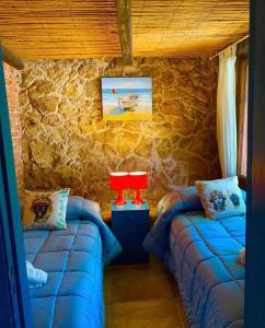 een kamer met 2 blauwe bedden in een stenen muur bij Blue Sea villa in Brucoli