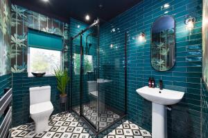 a blue tiled bathroom with a toilet and a sink at Fairview Boutique Apartments in West Bridgford Centre in Nottingham