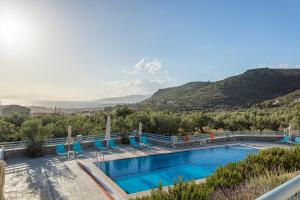 a swimming pool with chairs and a mountain in the background at Sundy Maria Apartments in Stoupa