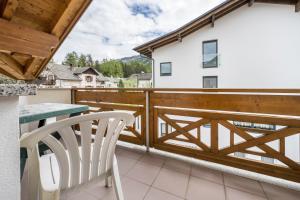 un balcón con una valla de madera, una mesa y una silla en Residence Oberhauser Apt 4 en Valdaora di Sopra