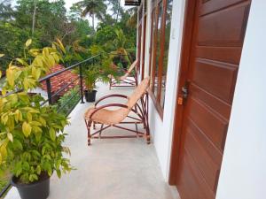a porch with a chair and some plants and a door at Saimon Villa in Mirissa