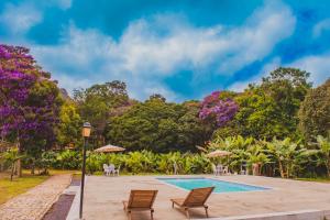 une piscine avec des chaises longues et des arbres en arrière-plan. dans l'établissement Villaflor Pousada, à Vale do Capão