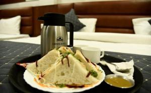 a sandwich on a plate on a table with a drink at HOTEL AASTHA SHREE DHAM in Lucknow