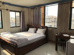 a bedroom with a bed and a desk and windows at RS Galaxy HOTEL in Phnom Penh