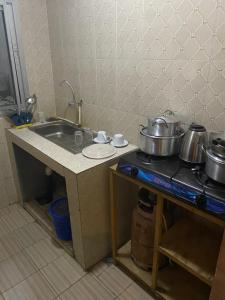 una cocina con ollas y sartenes en un mostrador junto a un fregadero en House Of Lottie, en Garoua