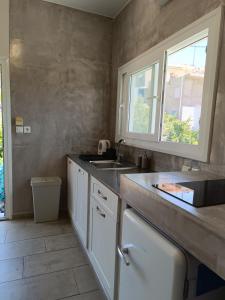 uma cozinha com armários brancos, um lavatório e uma janela em Nesea 2 em Psérimos