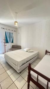 een witte slaapkamer met een bed en een stoel bij Pousada Capitolio 01 - Canoa Quebrada - hospedagem in Canoa Quebrada