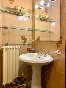 bagno con lavandino, specchio e radiatore di Trilocale Golf Club a Madonna di Campiglio